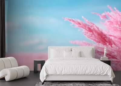   a pink plant in the foreground and a blue sky with clouds in the background Wall mural