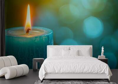   A tight shot of a lit candle against a softly blurred backdrop of blue and green lights Wall mural