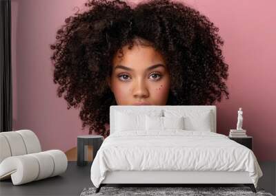   A woman's face, tightly framed in a close-up, displays frizzy hair against a soft pink backdrop Wall mural