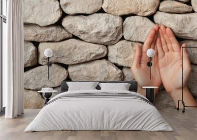  Two hands reach upward in front of a gray-white rock wall One hand elevated in front Wall mural