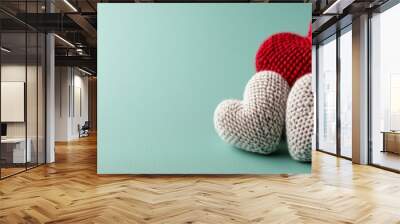  Two knitted hearts sit on a green surface against a light blue background Wall mural