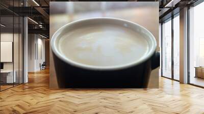 Coffee with milk in a black cup close-up. Coffee foam with milk in a cup Wall mural