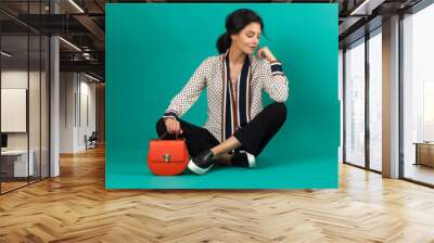 Fashion photography of young brunette model in the studio with green background Wall mural