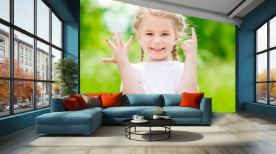 Beautiful blond little girl with two braids  showing six fingers (her age) and smiling on sunny day in summer park Wall mural