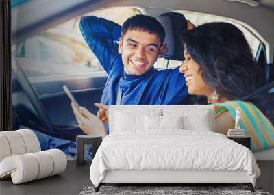 Beautiful indian couple in a car using mobile phone to plan their journey online Wall mural