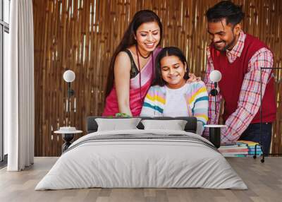 Beautiful traditional Indian family happily using laptop to check the exam marks of their cheerful little daughter Wall mural