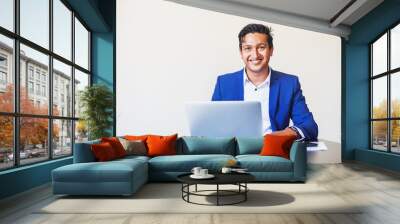 Handsome young professional Indian man in formal suit using laptop in the office over white background Wall mural