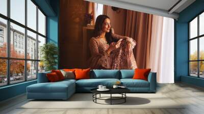 Rich beautiful Indian woman in luxury ethnic clothes using her phone in a 5 star hotel room. Filtered portrait in muted colors, film photography style Wall mural