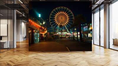 A carnival with a Ferris wheel is lit up at night Wall mural