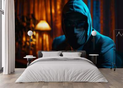 A man in a hoodie and glasses is sitting at a desk Wall mural