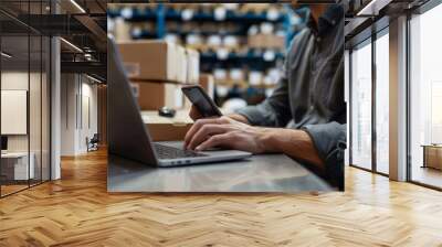 A man is using a laptop and a cell phone in a warehouse Wall mural