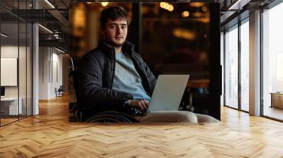 A portrait of a young man in a wheelchair, with a look of confidence on his face and a laptop on his lap Wall mural