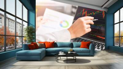 Business woman shows at graph on laptop and writing into notes or notebook.Computer screen with graphics and chart. Wall mural