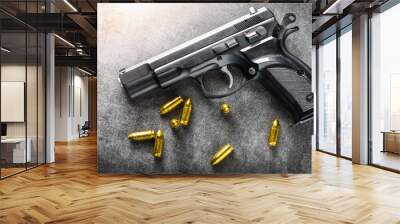 Detail of 9mm pistol, bullets and handcuffs. Gun with ammunition on dark stone background. Wall mural