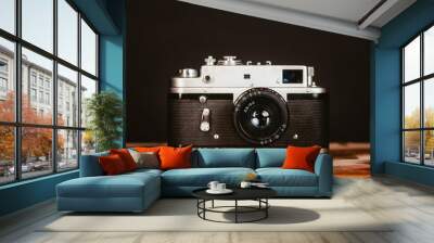 Vintage silver black analog film camera on a wooden table Wall mural