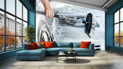 Manual car wash with brush and pressurized water in automobile washing station. Cleaning front bumper detail or close up at luxury cars. Wall mural