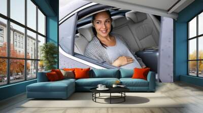 Beautiful young pregnant woman is driving in the car  Wall mural