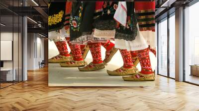 Girls dancing folk dance. People in traditional costumes dance Bulgarian folk dances. Close-up of female legs with traditional shoes, socks and costumes for folk dances. Wall mural