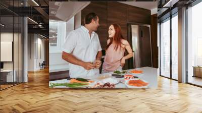 A couple, man and woman, cooking home sushi rolls laughing and having fun Wall mural