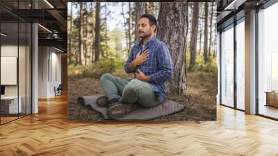 Adult man camper practice meditation and breath exercise in front tree Wall mural