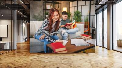 Adult woman write notes for exam, while adult man read a book Wall mural