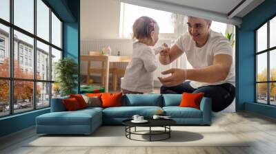 baby girl and her father young caucasian man with daughter playing at home happy sitting on the floor with toys in day fatherhood childhood family concept real people copy space Wall mural