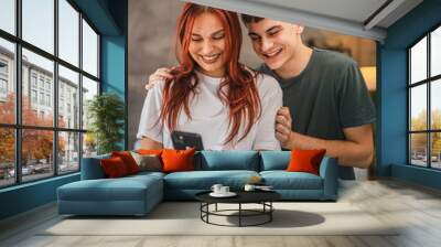 Beautiful young couple girlfriend and boyfriend use mobile at home Wall mural