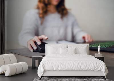 Close up on hand of young woman sitting at wooden table in the office holding mouse of the laptop computer working on the document selective focus in day Wall mural