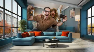 couple man and woman husband wife play smart phone video games at home Wall mural