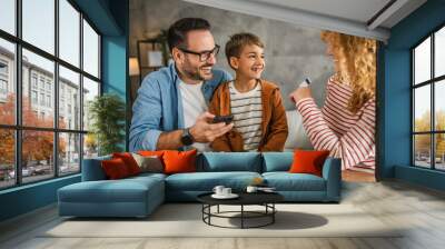 family of 3 have online shopping on mobile phone with credit card Wall mural