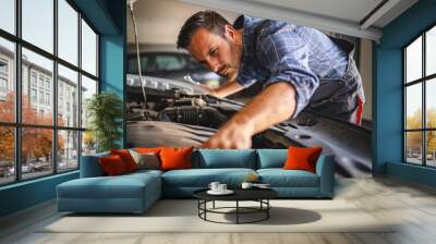 Focused car mechanic work under car hood in a garage setting Wall mural