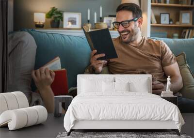 man and woman caucasian adult couple read books at home on sofa bed Wall mural