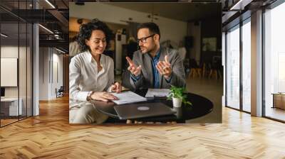 Man and woman colleagues hold documents and work together at cafe Wall mural