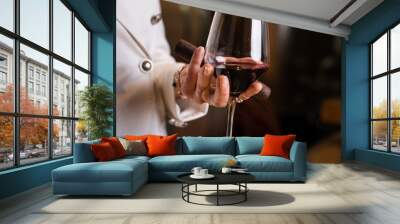 Midsection of one unknown caucasian woman holding glass of red wine in hand and cigar while standing indoor in cellar side view copy space drink and celebration concept Wall mural