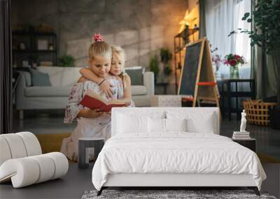 older friend sister help her young friend sister to read a book Wall mural