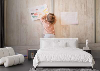 One baby girl back view full length of one infant child standing putting drawing on the wall at home real people copy space family childhood development and growing up concept Wall mural