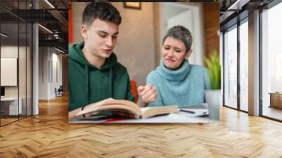 One student teenage caucasian man study learn with help of his tutor professor or mother senior woman at home having private lesson to prepare for exam education concept real people copy space Wall mural