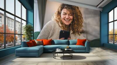 One woman with curly hair at home use mobile phone smartphone sms texting or browse internet Wall mural