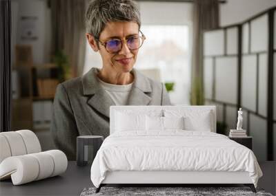 Portrait of mature woman stand and hold cup and document at office Wall mural