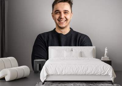 Portrait of one adult caucasian man 25 years old looking to the camera in front of white wall background smiling wearing casual black sweater copy space Wall mural