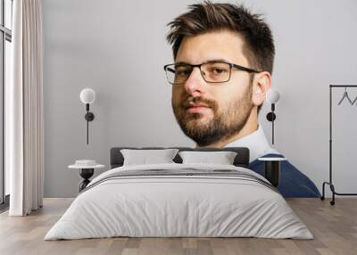 Portrait of one adult caucasian man 30 years old with beard and eyeglasses looking to the camera in front of white wall background wearing sweater young businessman success concept copy space Wall mural