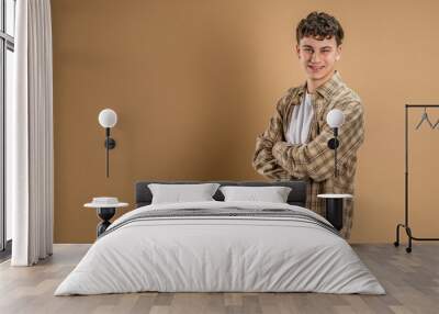 Portrait of one caucasian man 20 years old looking to the camera in front of almond color studio background smiling wearing casual shirt copy space Wall mural