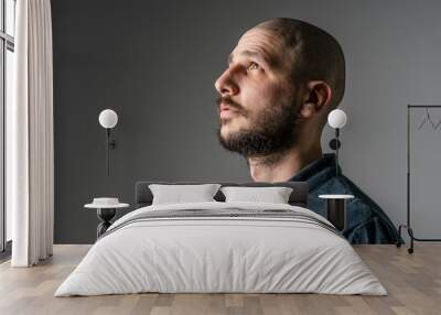 Side view close up portrait of adult caucasian man with beard and short hair looking up thoughtful with copy space - studio shot Wall mural