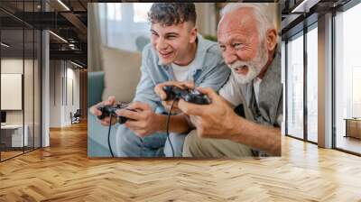 teenager male and his grandfather senior man play console video game Wall mural