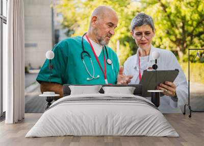 Two healthcare professionals review tablet outdoor in uniforms Wall mural