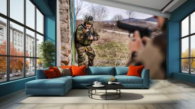 Two men soldiers in uniform braking in to the house ruin during mission battle operation dogs of war volunteers mercenaries contractor secure the building armed service holding rifles pointed Wall mural