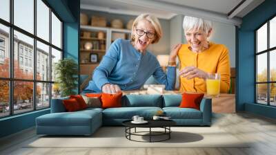 two senior women friends or sisters play leisure board game at home Wall mural