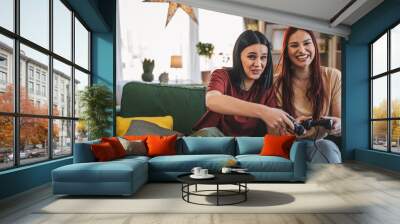 Two young women caucasian friends or sisters play console video game Wall mural