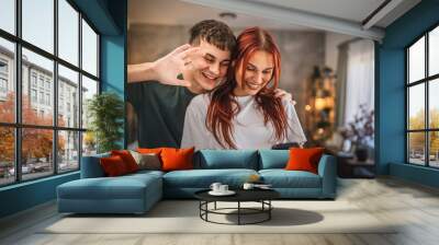 Welcoming young couple waving during video call on mobile phone Wall mural