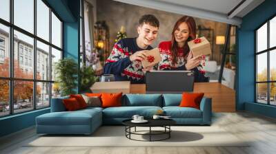 Young couple show gift during video call, holiday spirit shines bright Wall mural